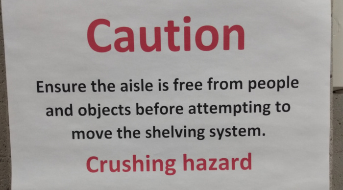 Warning sign on compact shelving: Crushing hazard